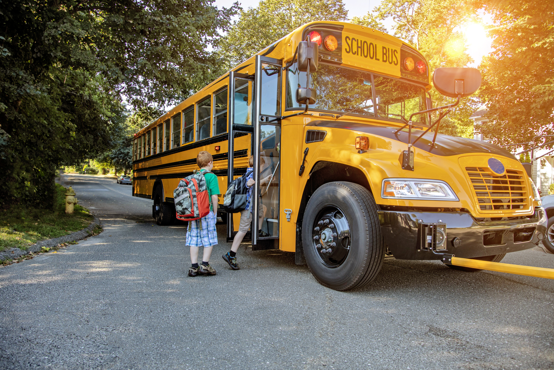 A school bus, one of many propane fleet vehicles, stops to pick up children on a sunny morning.